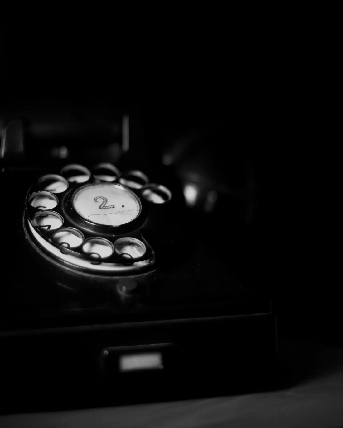 A rotary telephone dial, lit against the dark
